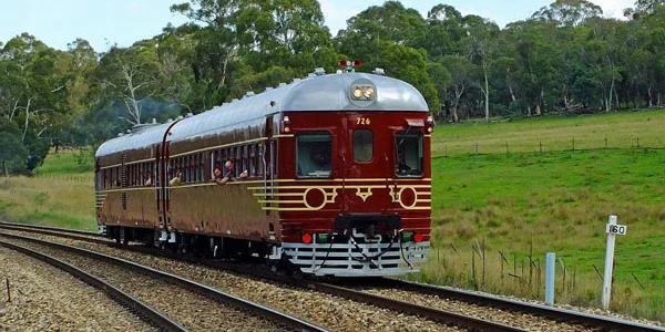 Photo of the Byron Bay Train in motion with farmland in background