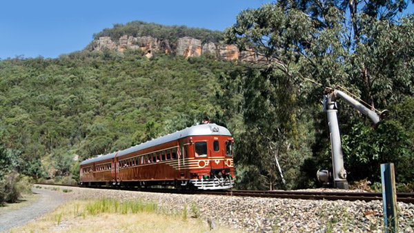Photo of the Byron Bay Train in motion with mountain in background